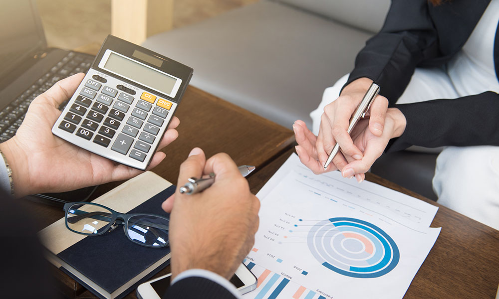 Dos personas con una calculadora y gráficos de contabilidad