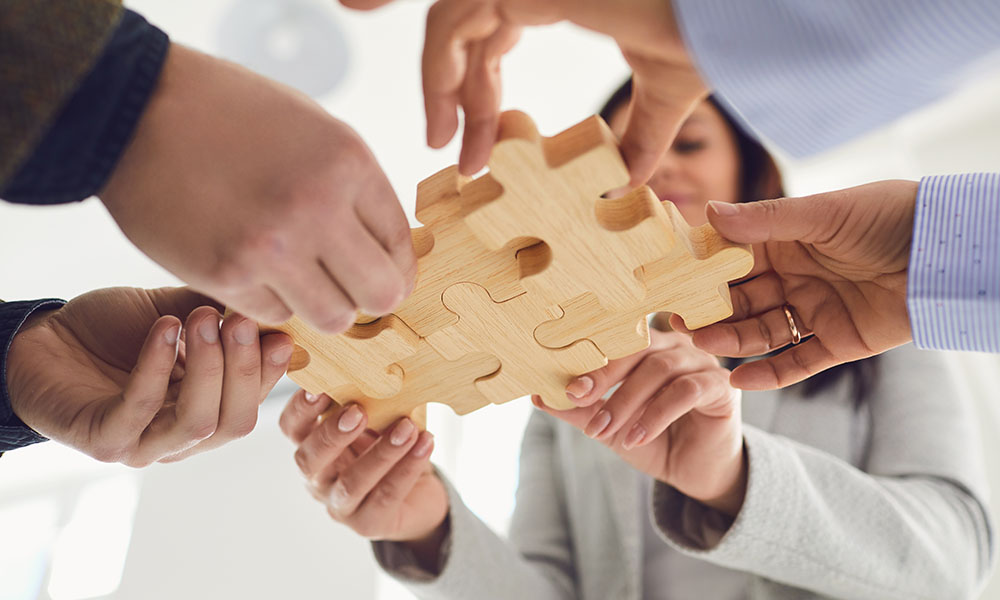 Una project manager sosteniendo piezas de puzzle con su equipo