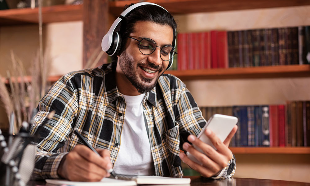 Un hombre con auriculares y teléfono móvil usando las redes sociales como herramienta dinamizadora